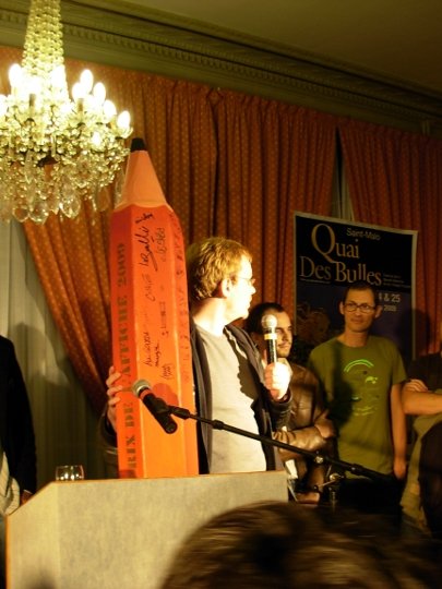 Boulet, brandissant son gros crayon rouge, devant Bernard Cosey médusé